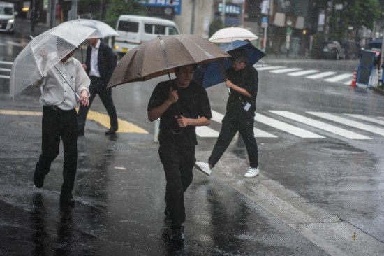　　6月3日，在日本东京，行人撑伞在街头行走。新华社记者贾浩成摄