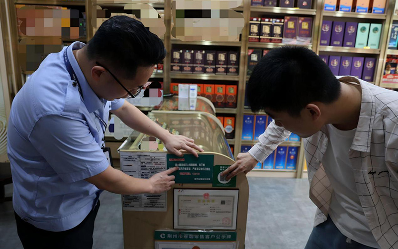 市管员帮助零售户粘贴警示标语。